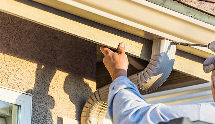 A person is repairing gutter at house A person is repairing gutter at house